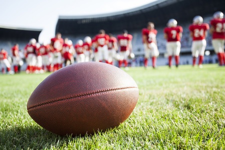 Photo: Cose Up Of An American Football On The Field, Players In The Background